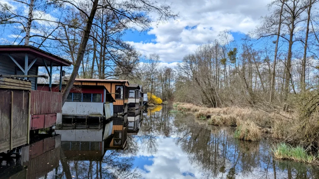 Bootshäuser spiegeln sich im Wasser nahe dem Kremmener See