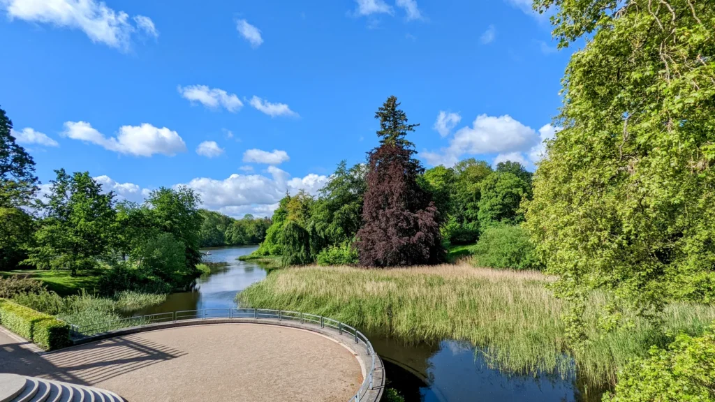Halbrunde Terrasse an einem Wassergraben im Schlosspark Putbus, dahinter eine Blutbuche