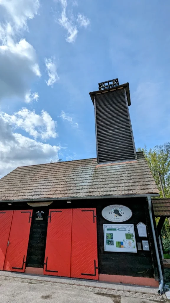 Feuerwehrhaus in Lehde mit roten Toren, Turm und Schild