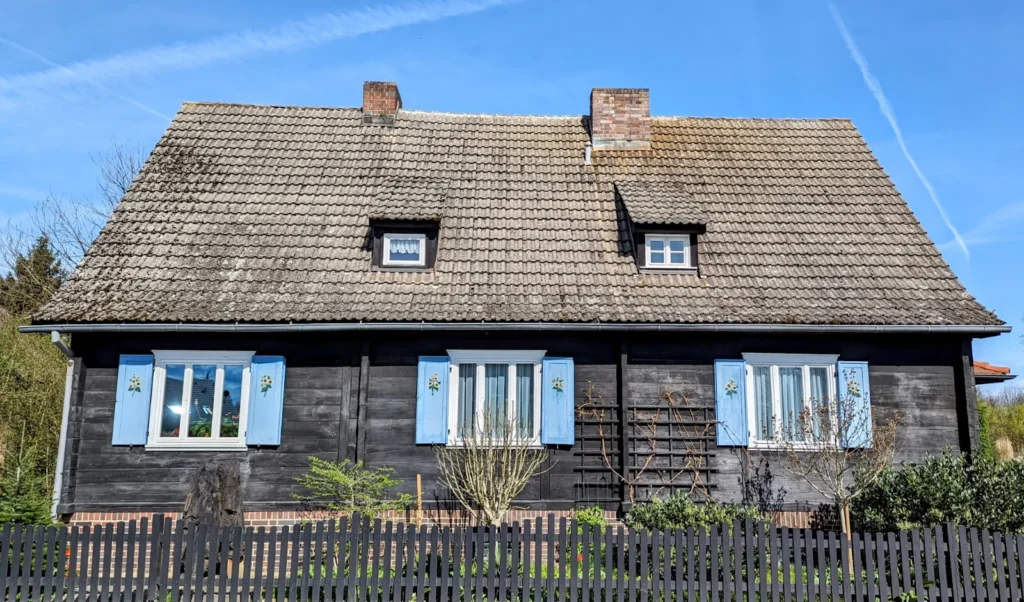 Dunkles Holzhaus mit Schindeldach und blauen Fensterläden in Lübbenau