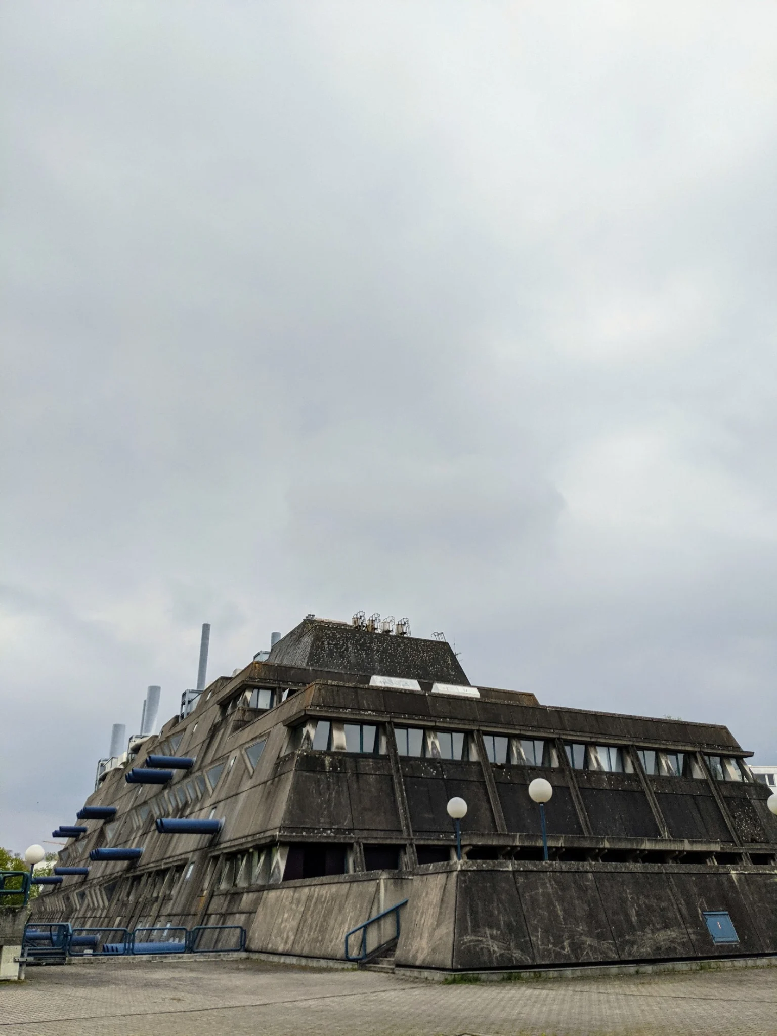 Der Mäusebunker 2021 unter grauem Himmel, Blick auf die Stirnseite mit Rohren und Dachaufbau