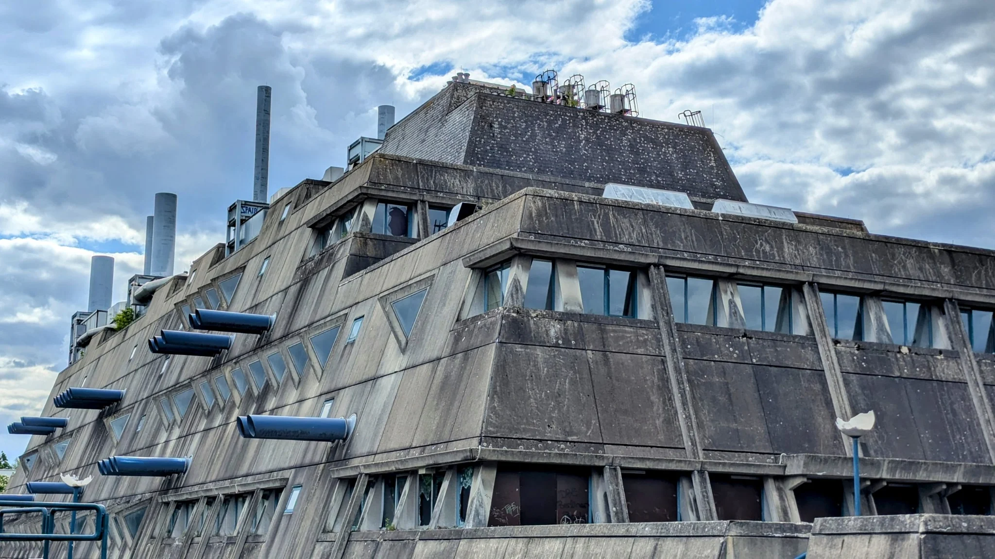 Fassade des Mäusebunkers mit schrägen Betonflächen, dreieckigen Fenstern und blau gestrichenen Zuluftrohren