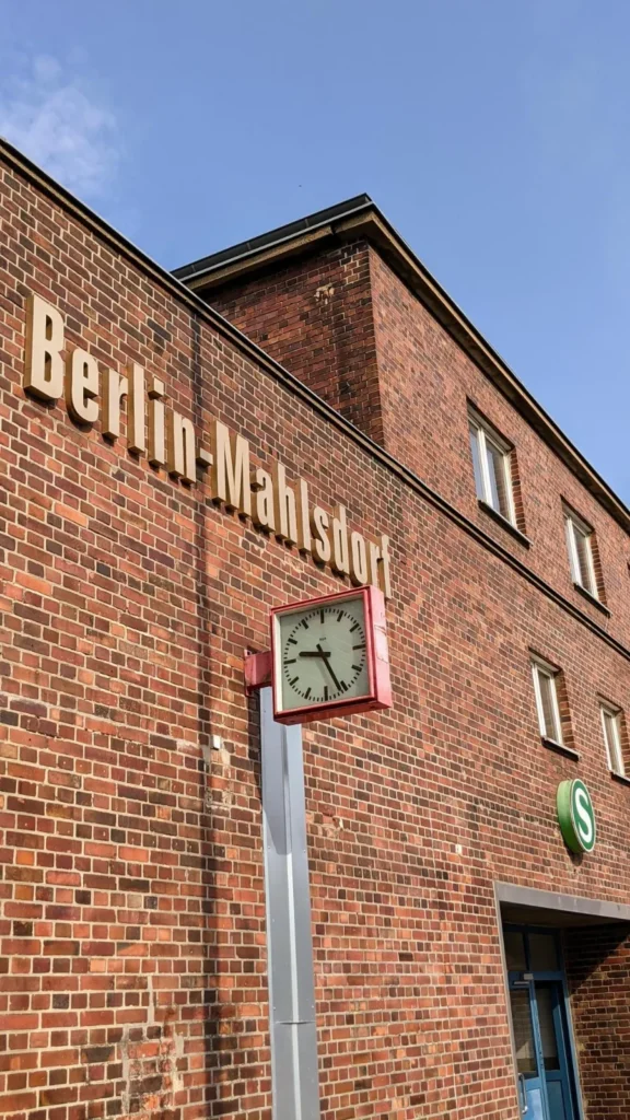 Bahnhofsgebäude aus rotem Backstein mit Schriftzug Berlin-Mahlsdorf, Uhr und S-Bahn-Zeichen am S-Bahnhof Mahlsdorf