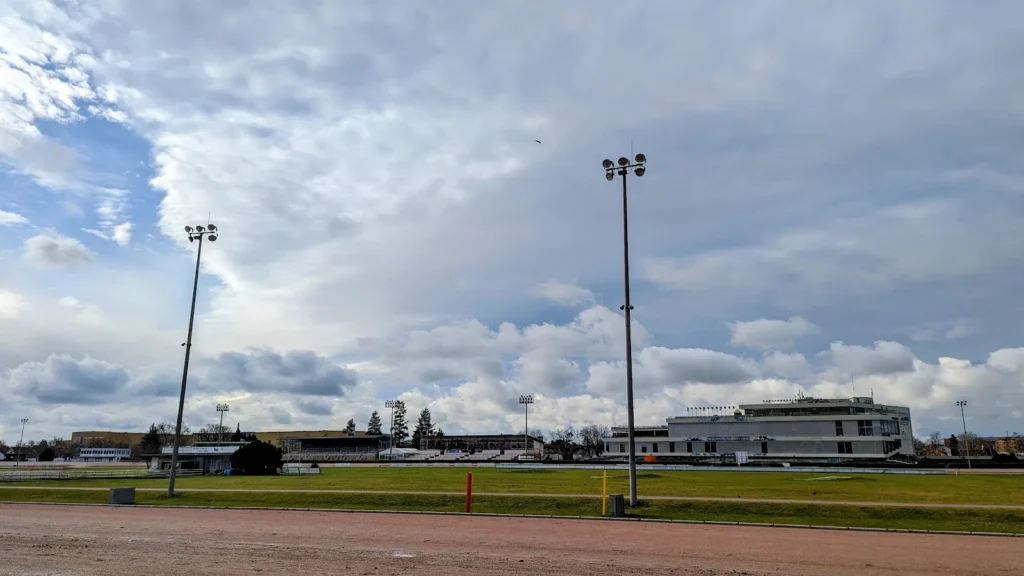 Sandbahn und Rasen der Trabrennbahn Mariendorf mit Flutlichtmasten und Tribünenbauten