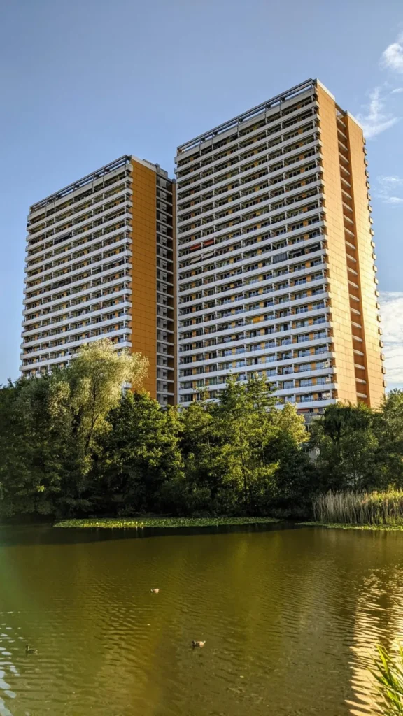 Orangefarbenes Doppelhochhaus hinter einem Teich am Springpfuhl in Marzahn