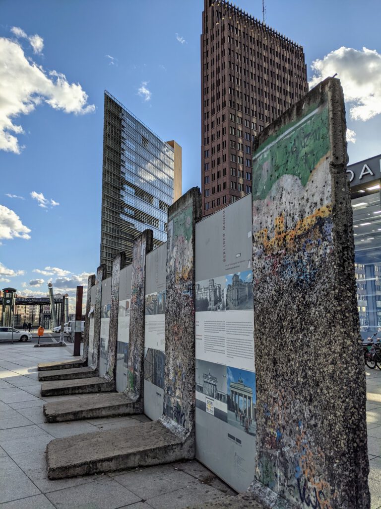 Reihe einzelner Mauersegmente mit Infotafeln auf dem Potsdamer Platz, dahinter Hochhäuser