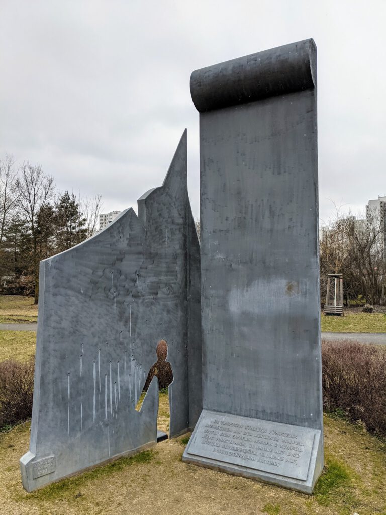 Denkmal aus zwei grauen Metallwänden, in eine ist die Silhouette eines Kindes geschnitten, davor liegt eine Tafel mit Inschrift