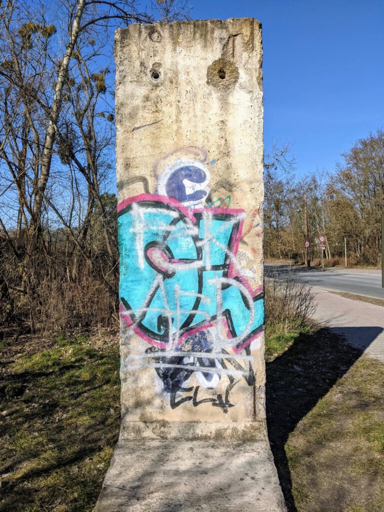 Drei Mauersegmente, auf die in Schwarz-Weiß je ein Porträt gemalt ist