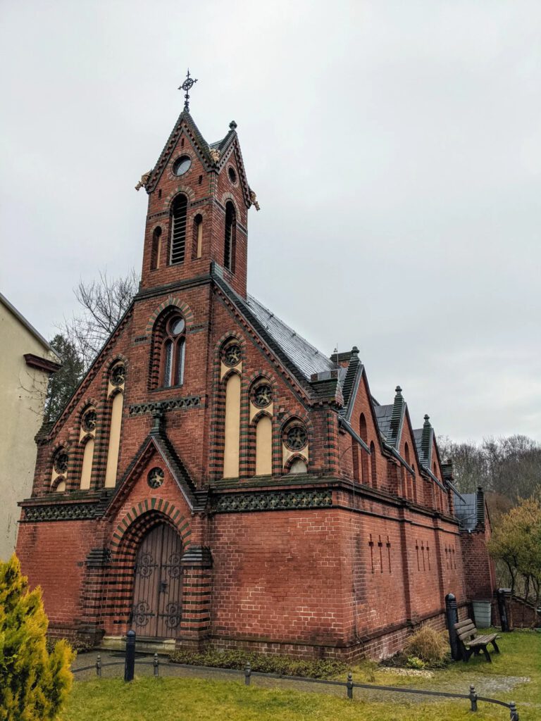 Neugotische Kapelle aus rotem Backstein mit grün glasierten Zierbändern und einem kleinen Turm