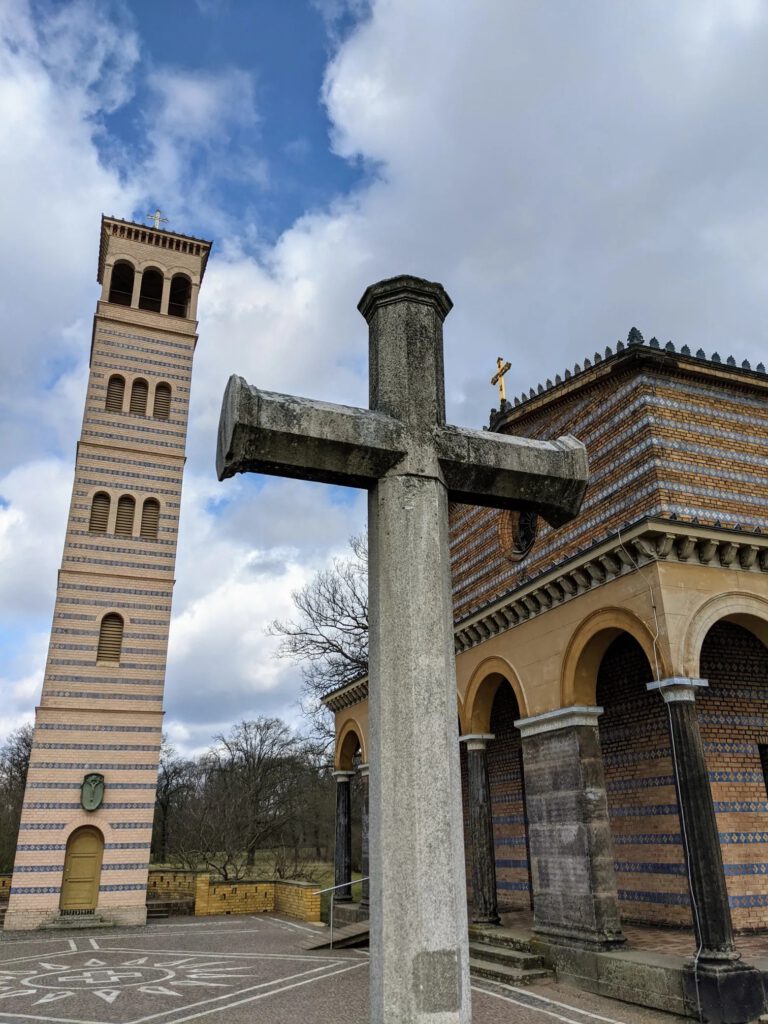Steinkreuz vor der Heilandskirche, links der gestreifte Glockenturm, rechts der Arkadengang