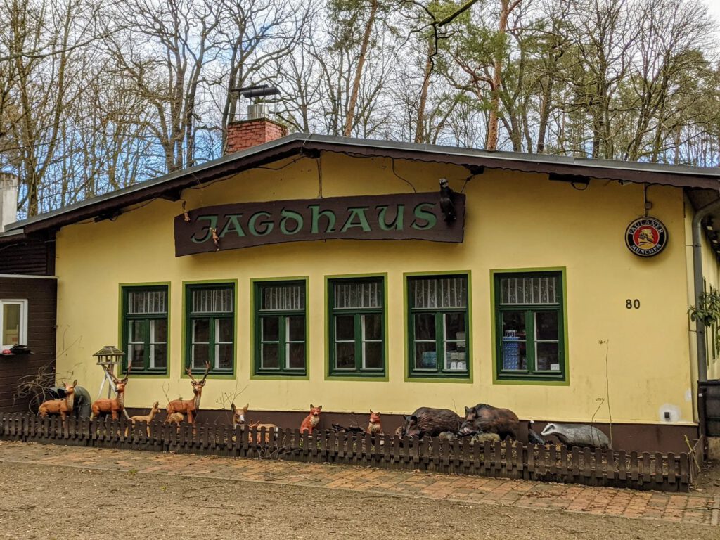 Gelbes Ausflugslokal mit dem Schriftzug „Jagdhaus“, vor der Fassade stehen Tierfiguren von Rehen, Füchsen, Wildschweinen und einem Dachs
