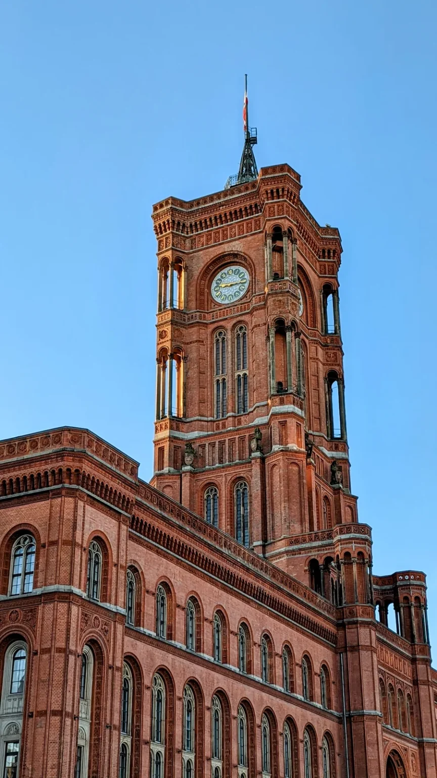 Turm und Backsteinfassade des Roten Rathauses mit Uhr vor wolkenlosem blauem Himmel