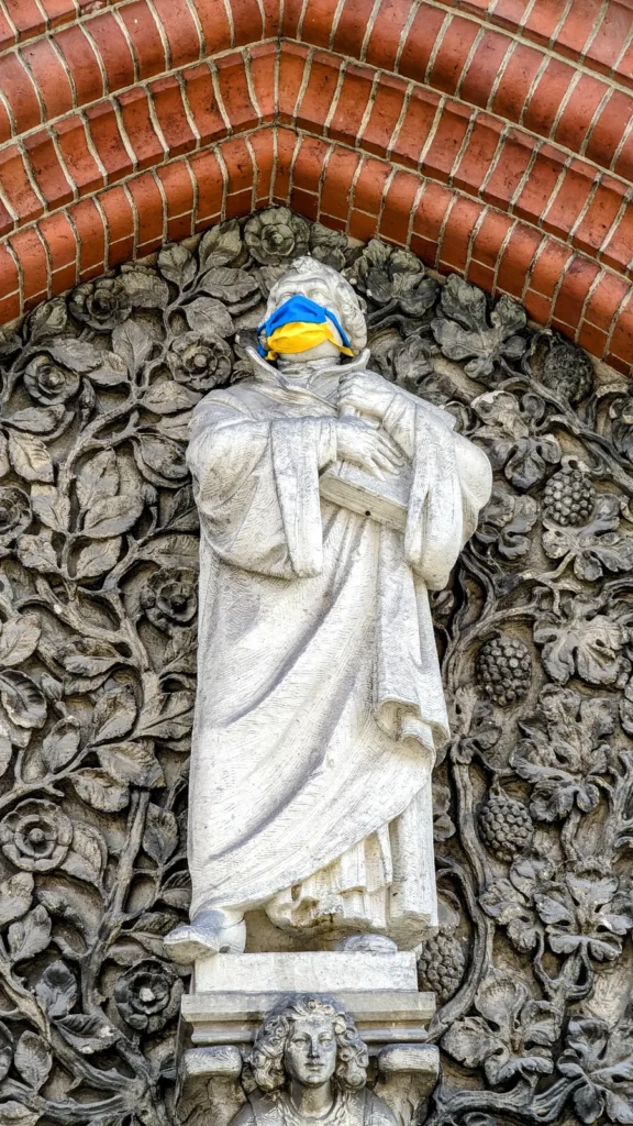 Sandsteinfigur Martin Luthers über dem Portal der Reformationskirche in Moabit, mit blau-gelber Maske