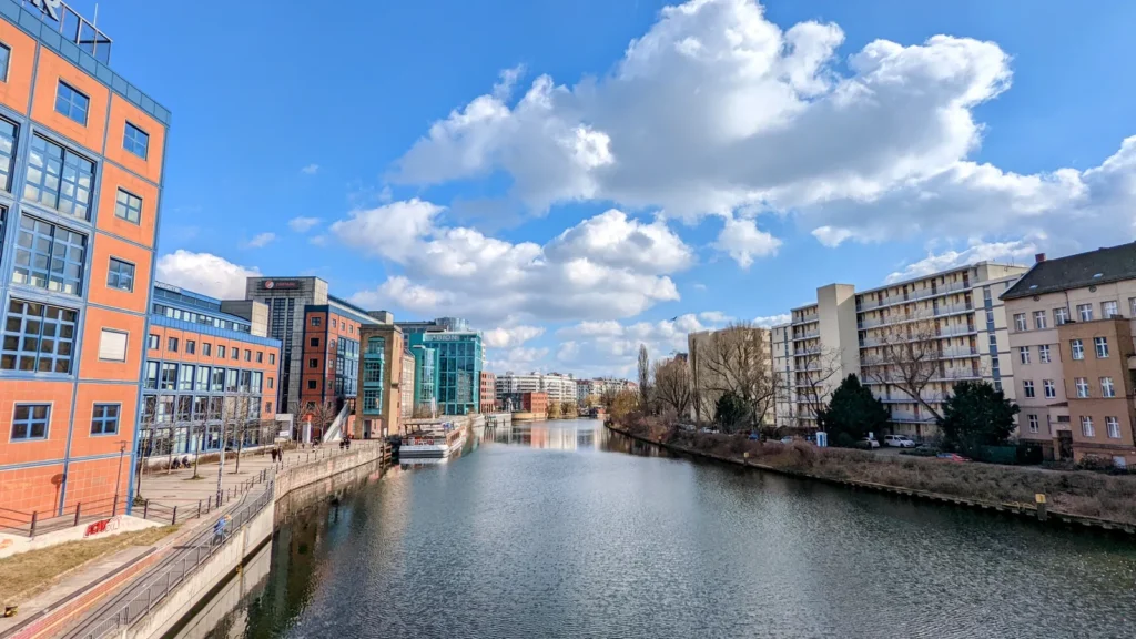 Die Spree in Moabit mit Uferbebauung auf beiden Seiten und Wolken am blauen Himmel