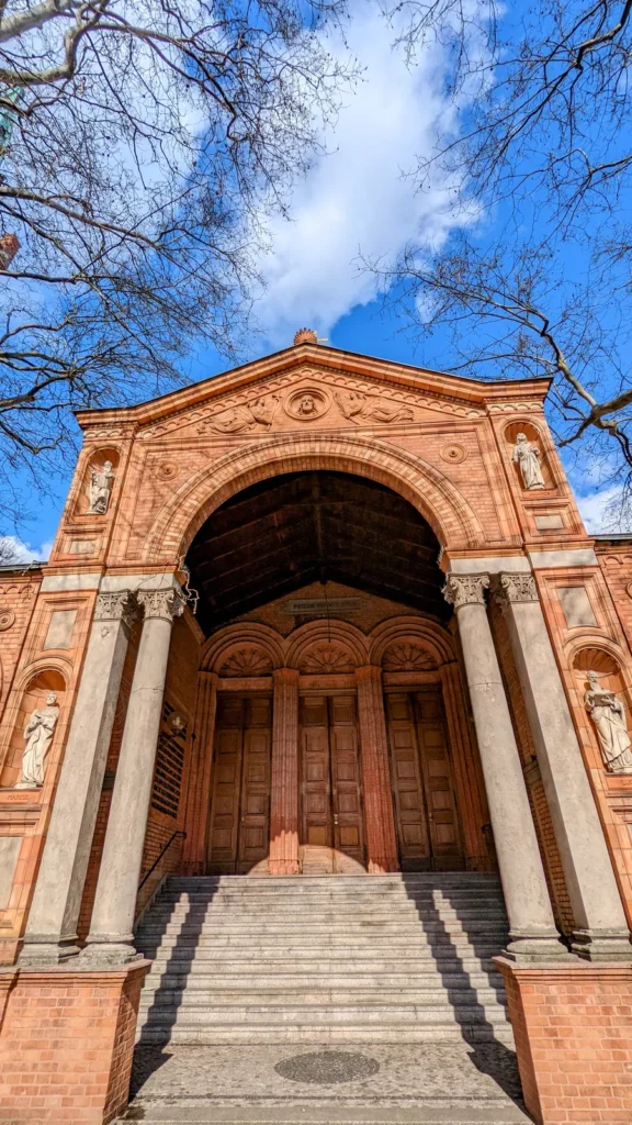 Offene Vorhalle von St. Johannis in Moabit mit Säulen, Torbogen, Figuren und Holztüren