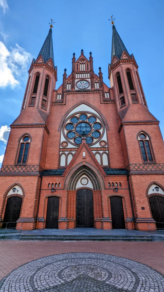 Zweiturmfassade der Backsteinkirche St. Paulus in Moabit mit Fensterrose, Staffelgiebel und gepflastertem Vorplatz