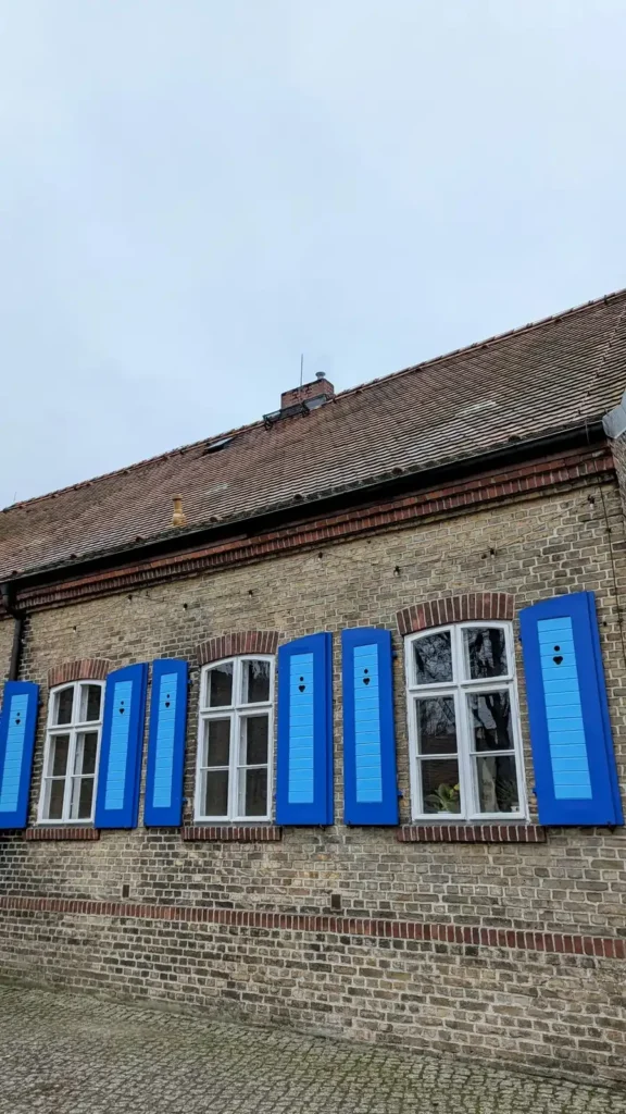 Altes Haus mit blauen Fensterläden am Dorfanger Alt-Müggelheim an einem Wintertag mit kahlen Bäumen