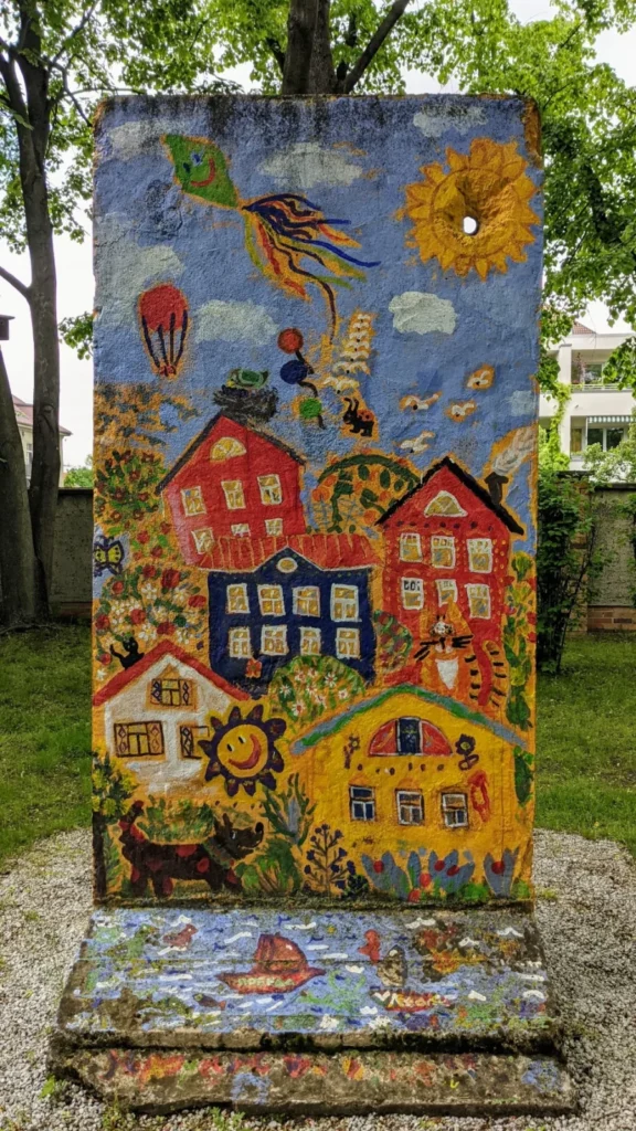 Bemaltes Mauersegment im Museumsgarten mit Häusern, Sonne und Drachen