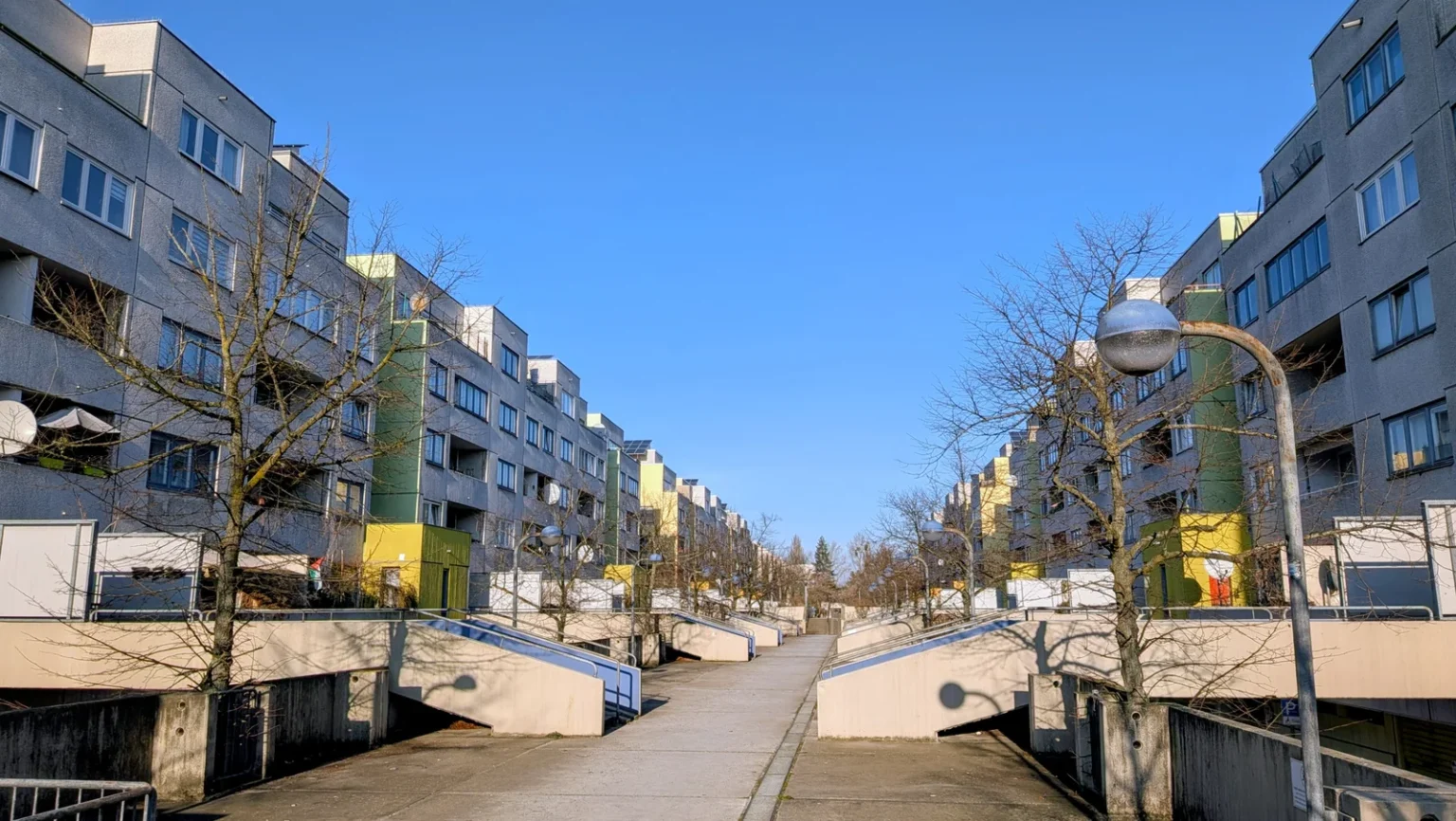 Hochdeck der High-Deck-Siedlung in Neukölln: mehrgeschossige Wohnzeilen mit Balkonen und farbigen Fassadenteilen beiderseits eines erhöhten Fußwegs, Rampen an den Seiten