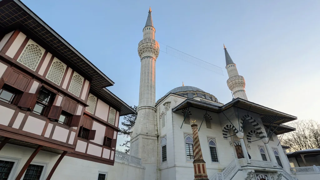 Şehitlik-Moschee in Neukölln mit zwei Minaretten und Holzhaus am Columbiadamm im Abendlicht