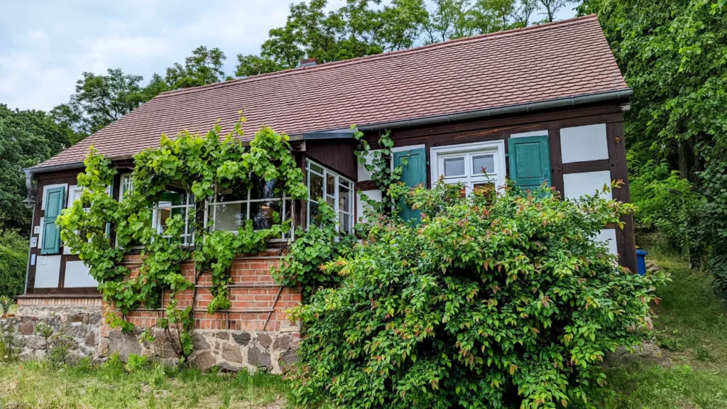 Fontanehaus in Schiffmühle, ein niedriges Fachwerkhaus mit grünen Fensterläden und bewachsener Veranda