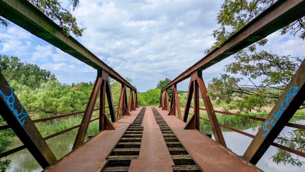 Rostige Stahlfachwerkbrücke der stillgelegten Bahn über die Alte Oder bei Bad Freienwalde, zwischen den Trägern liegen Riffelbleche