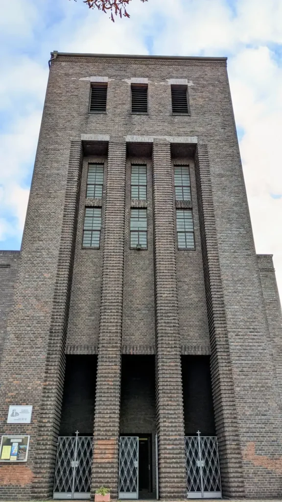 Kirchturm aus dunklem Klinker mit hohen, schmalen Fensterbändern in Niederschöneweide