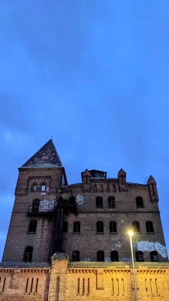 Backsteinbauten der früheren Bärenquell-Brauerei mit Turm an der Schnellerstraße in Niederschöneweide in der Dämmerung