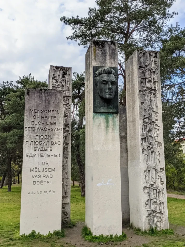 Julius-Fučík-Denkmal im Bürgerpark Pankow: hohe helle Stelen mit Inschrift und Porträtkopf