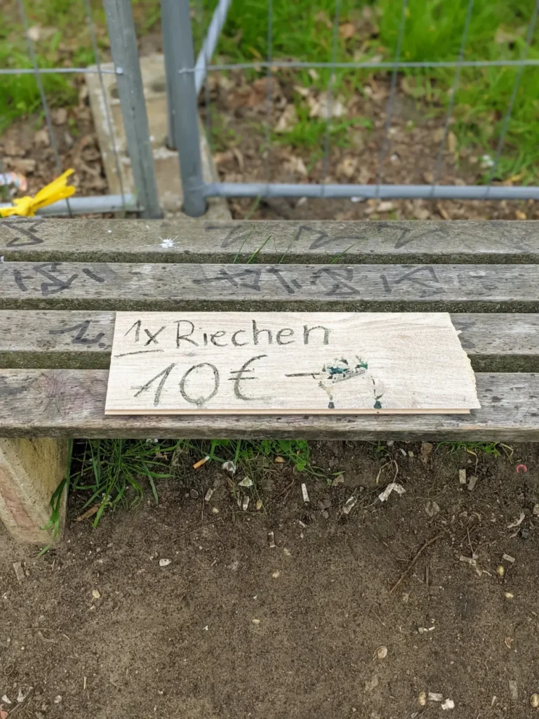 Handgeschriebenes Schild „1x Riechen 10 €“ auf einer Bank in Zepernick