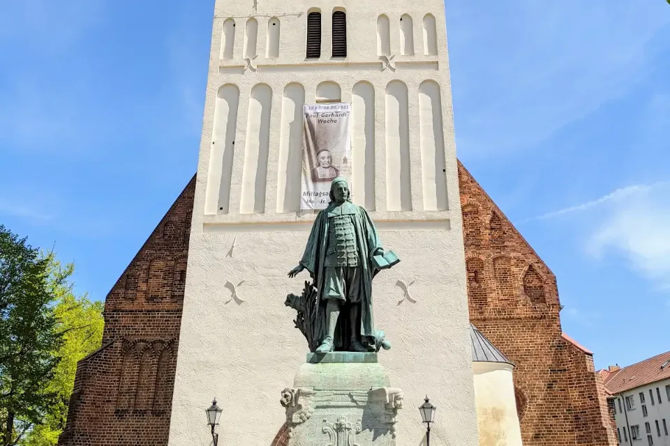 Turm der Paul-Gerhardt-Kirche in Lübben mit dem Denkmal davor