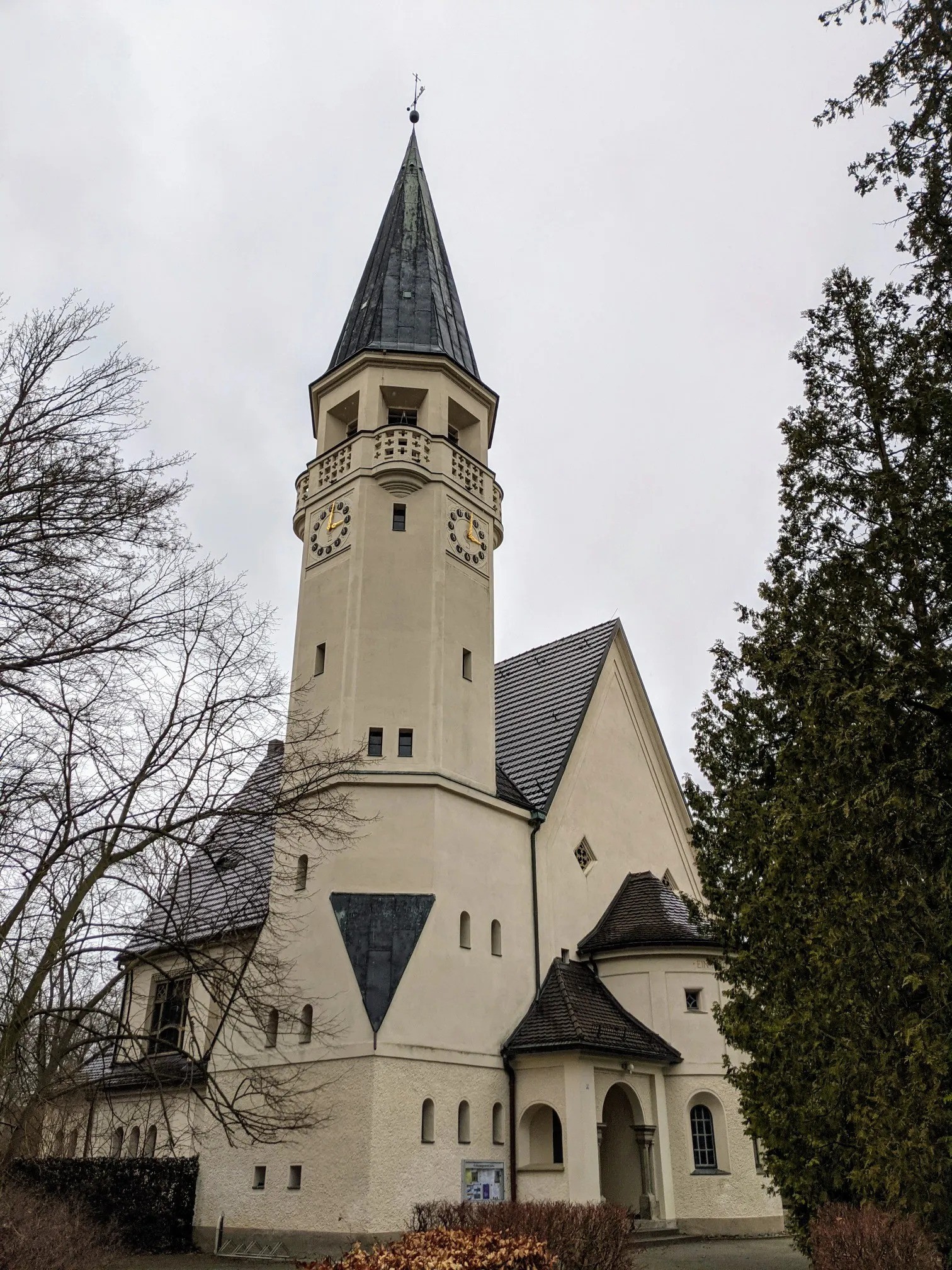 Helle Kirche mit hohem Turm und zwei goldenen Zifferblättern