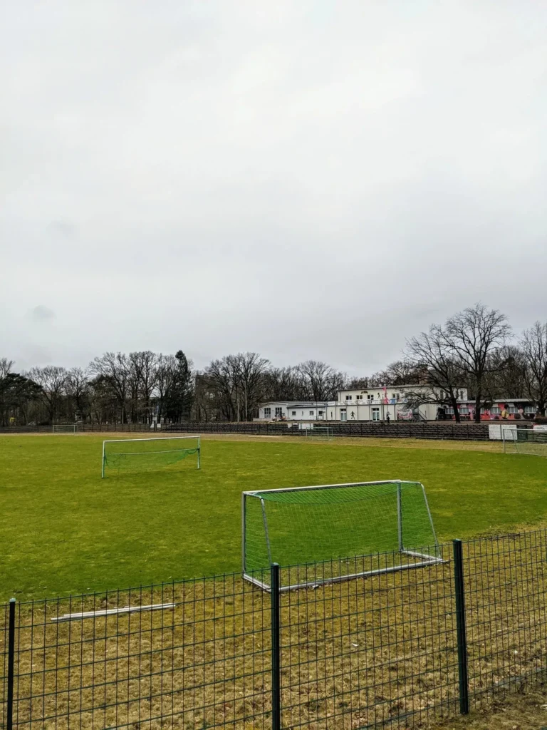Sportplatz mit Fußballtoren und Vereinsheim unter grauem Himmel