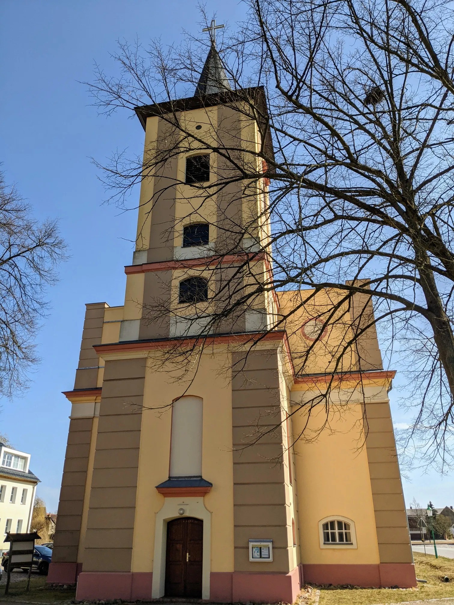 Gelbe Kirche mit Turm vor blauem Himmel
