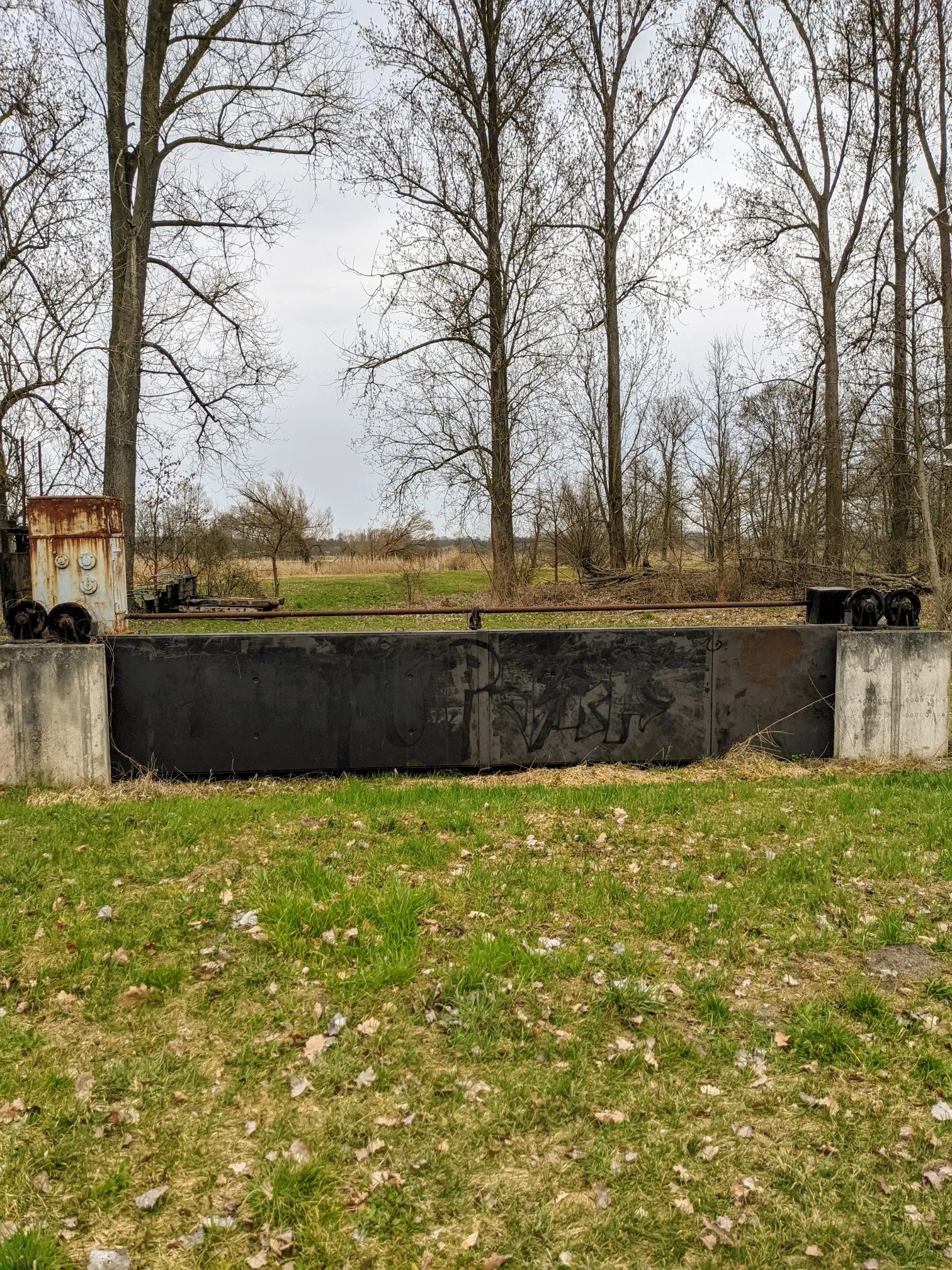 Stillgelegte Stauanlage mit rostigem Aufbau und Graffiti