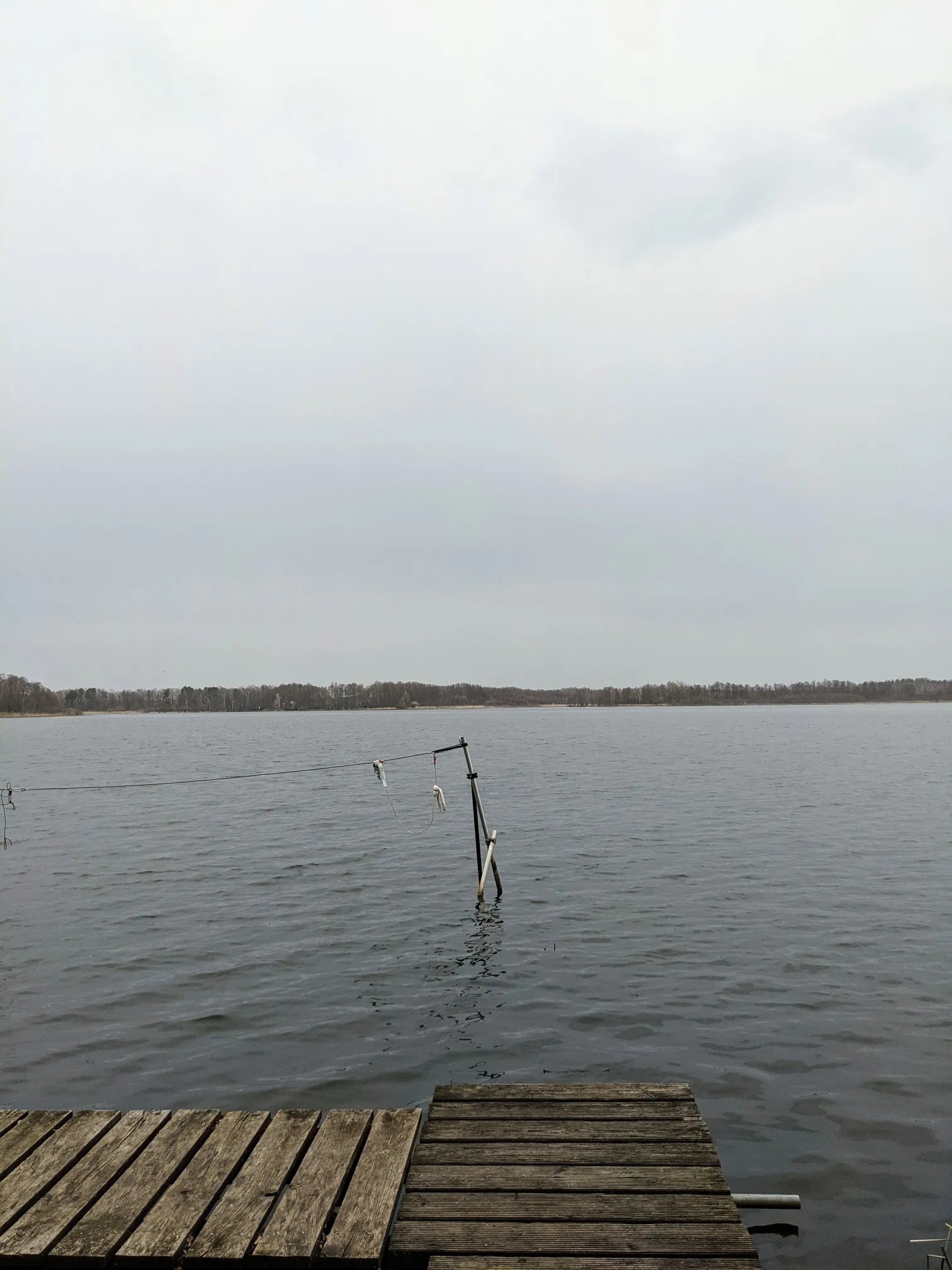 See mit Steg und einer Stange im Wasser