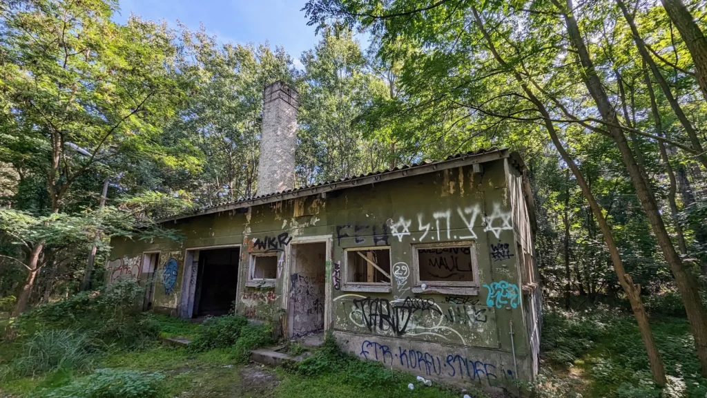 Verfallener Flachbau mit Graffiti und Schornstein im Kiefernwald bei Peenemünde
