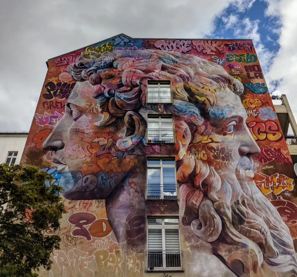 Wandbild Janus von PichiAvo an der Friedrichstraße in Berlin-Kreuzberg: zwei antike Köpfe im Profil, einer mit Locken, einer mit Bart, überlagert von Graffiti