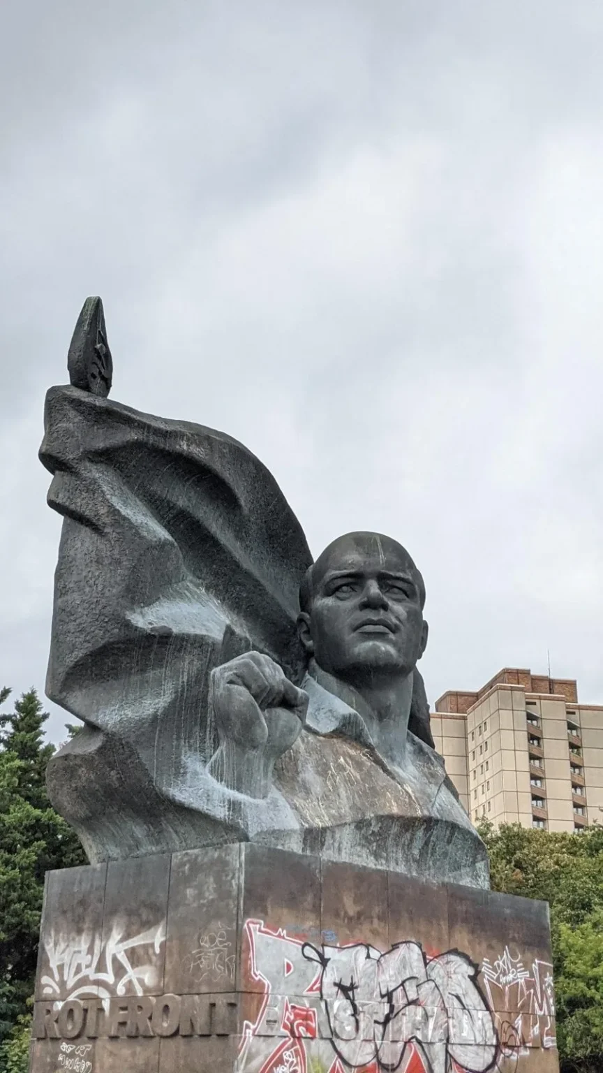Ernst-Thälmann-Denkmal im Ernst-Thälmann-Park, dunkle Skulptur auf einem Sockel mit Graffiti