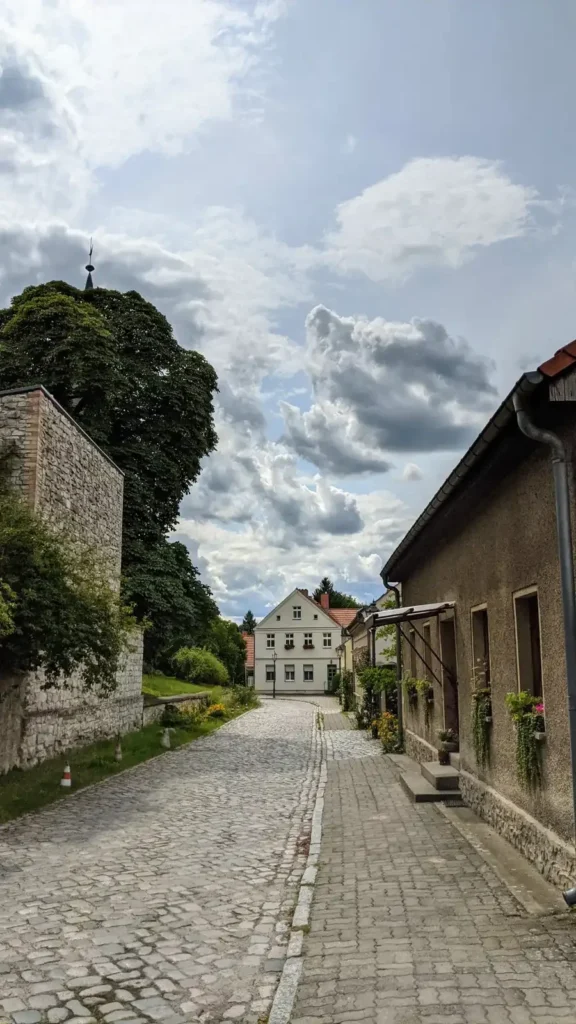 Kopfsteinpflaster und niedrige Häuser im alten Fischerdorf Rahnsdorf am Dorfanger im Sommer
