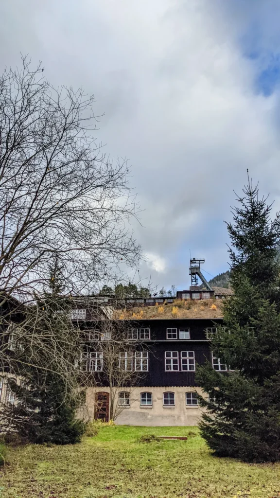 Dunkles Fachwerkgebäude am Hang des Rammelsbergs, dahinter das Fördergerüst