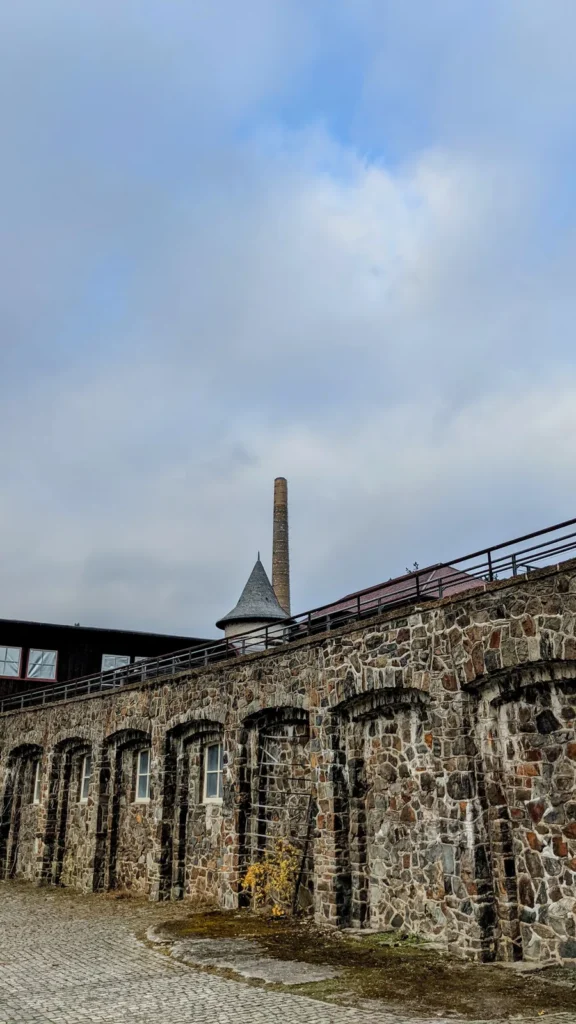 Schornstein und Türmchen hinter einer Bruchsteinmauer mit Rundbögen am Rammelsberg
