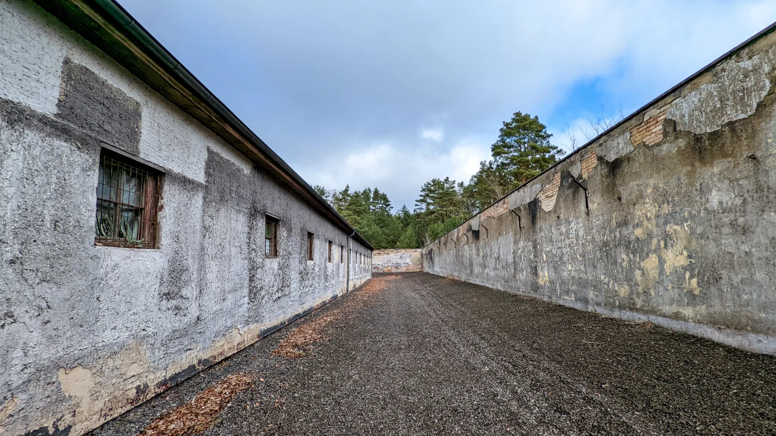 Hallenwand und Mauer entlang eines Wegs im Industriehof der Gedenkstätte Ravensbrück