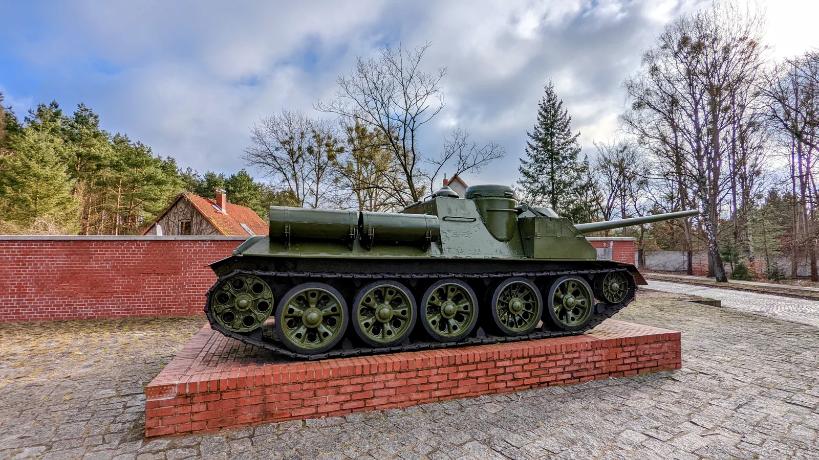 Sowjetisches Geschütz SU-100 auf einem Sockel vor einer Backsteinwand an der Straße der Nationen