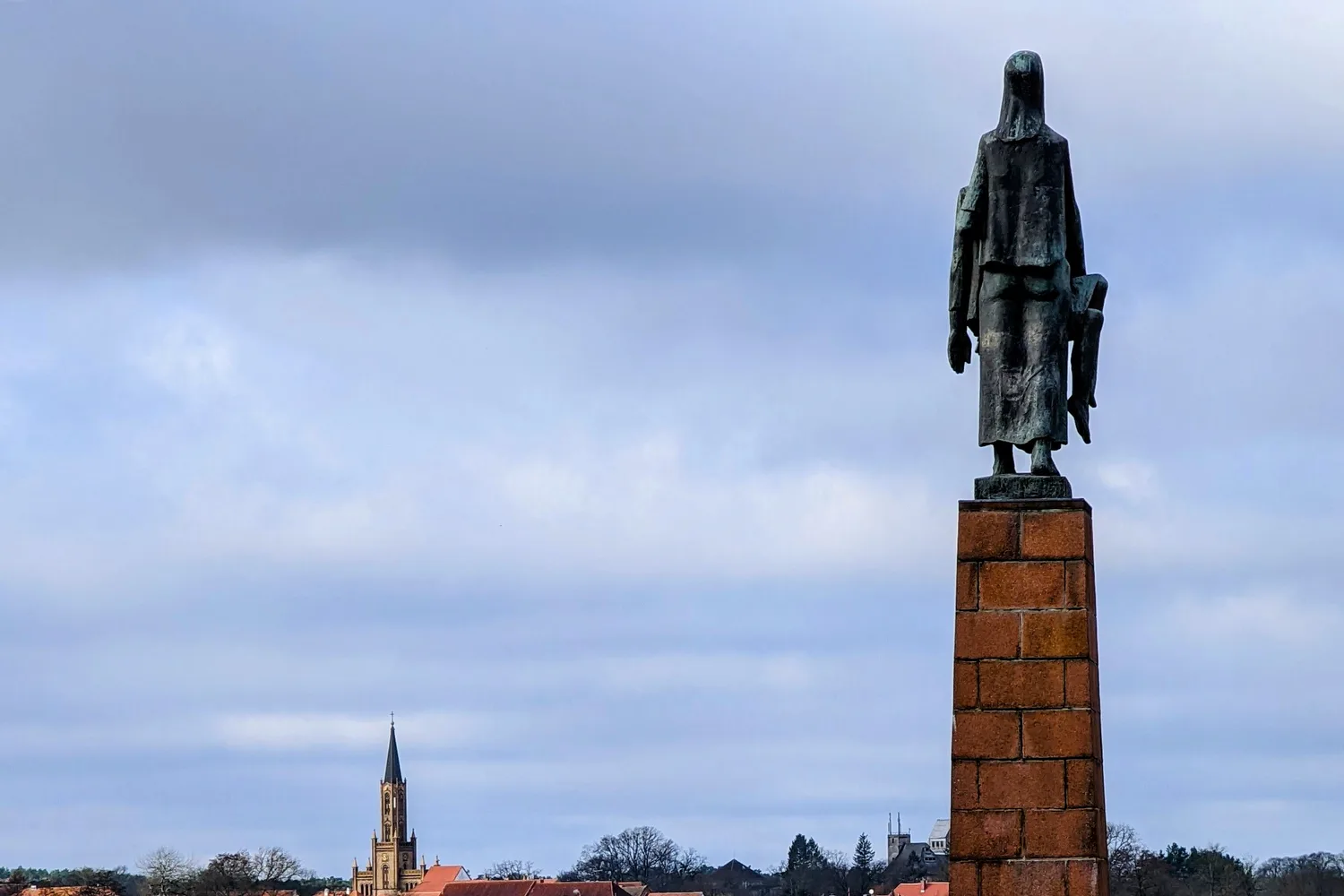 Die Tragende von Will Lammert auf ihrem Sockel am Schwedtsee, dahinter die Stadt Fürstenberg/Havel