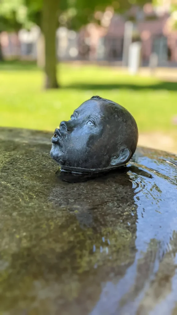 Bronzekopf auf einem nassen Stein in Rheinsberg