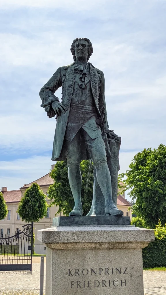 Bronzedenkmal des Kronprinzen Friedrich vor Schloss Rheinsberg mit Inschrift auf dem Sockel