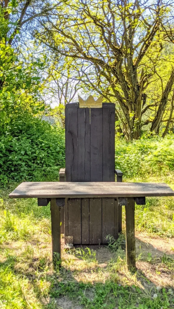 Großer Holzsitz mit Krone auf der Lehne im Wald nördlich von Rheinsberg