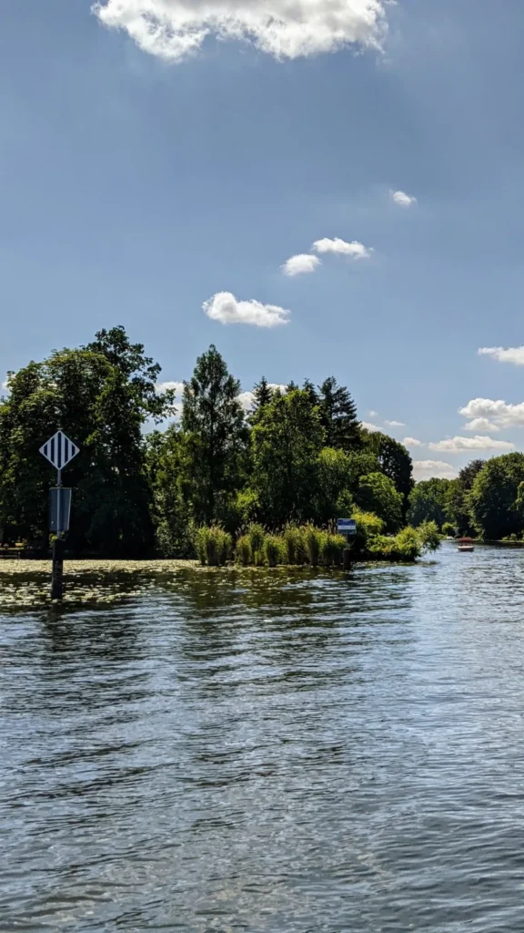 Müggelspree mit Bäumen am Ufer und einem Schild am Wasser