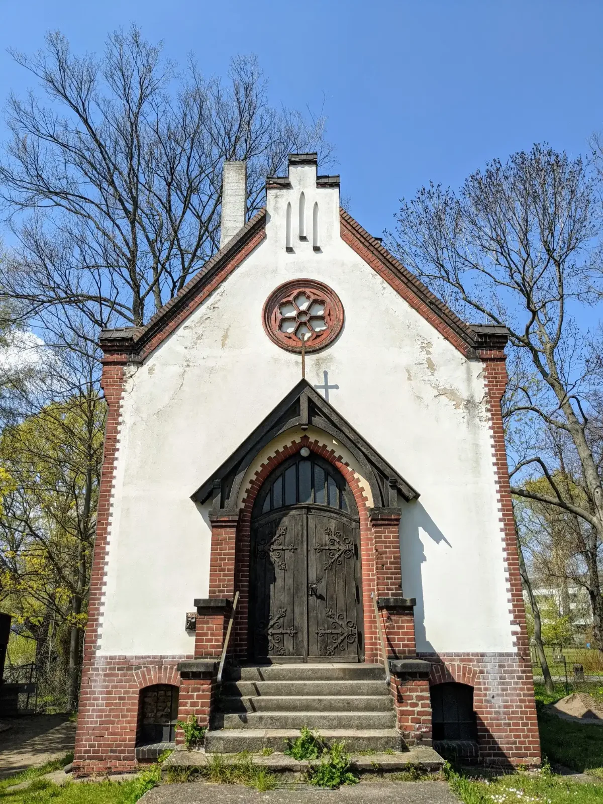 Weiß verputzte Kapelle mit Backsteinkanten und Rosettenfenster auf dem Friedhof Stralau